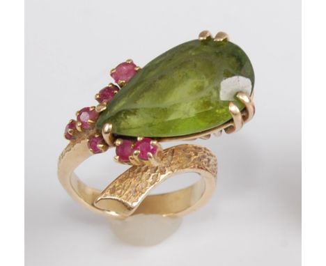 A yellow metal Lariat style peridot and ruby cocktail ring, the pear shaped peridot measuring approx 19 x 11.5 x 7.35mm, weig
