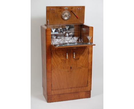 An Art Deco figured walnut cocktail cabinet, having typical twin hinged upper compartment enclosing mirrored interior with su