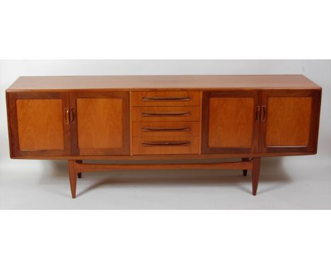A 1960s G-Plan teak long sideboard, having four central drawers, flanked by twin recessed panel cupboard doors, each with int
