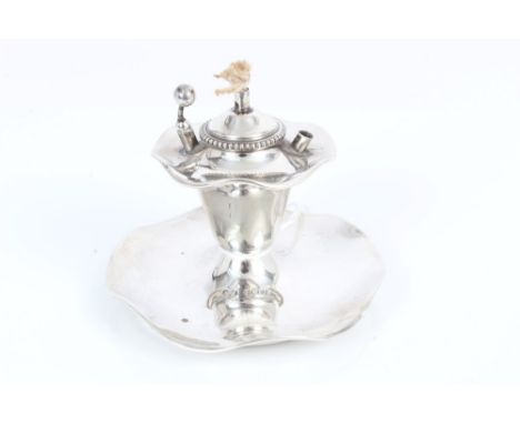 Edwardian silver table lighter and ashtray of shaped circular form, with central wick and two wadding holders (one missing) (