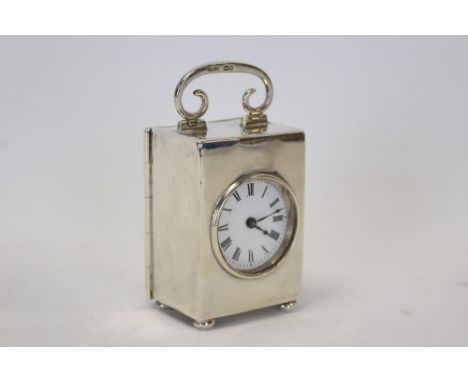 Edwardian miniature carriage clock with French movement and circular white enamel dial mounted in a silver case with scroll h