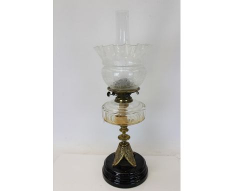 Early 20th century brass oil lamp with etched glass shade and faceted clear glass reservoir, on brass column and ceramic base