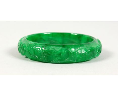 A CARVED APPLE GREEN JADE BANGLE. 3ins diameter.