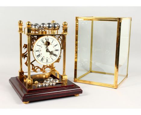AN UNUSUAL BRASS CLOCK, with rolling ball movement and floral decorated dial, in a glass display case. 16ins high.