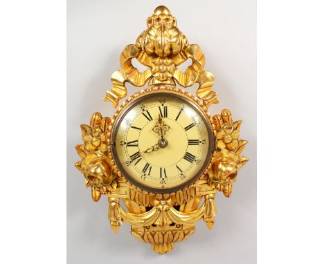 A CARVED GILTWOOD CARTEL WALL CLOCK. 20ins high.