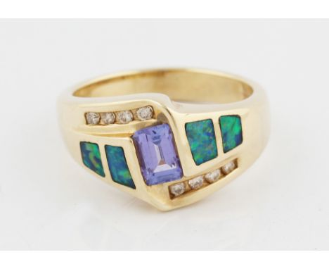 A tanzanite, opal and diamond ring, set with a central emerald cut tanzanite, flanked to either side with two opal panels and