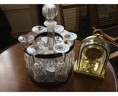 A mahogany decanter and glasses holder together with a modern quartz clock.