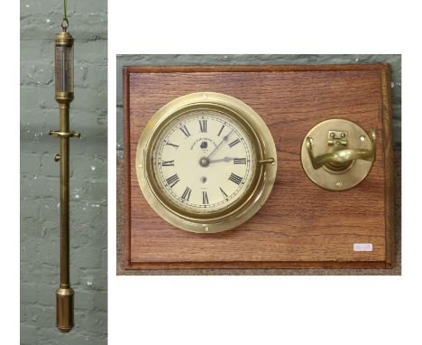 A brass marine stick barometer and bulk head clock mounted on a wooden plinth, the barometer on a gimble.