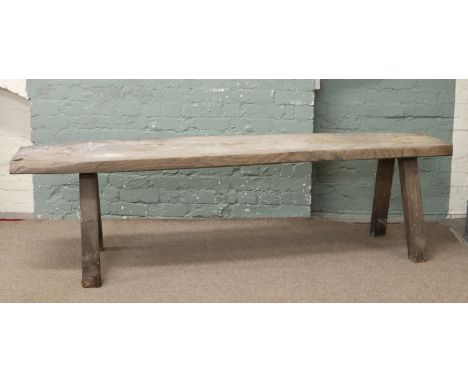 A period burr elm bench raised on splayed square supports, length 220cm.