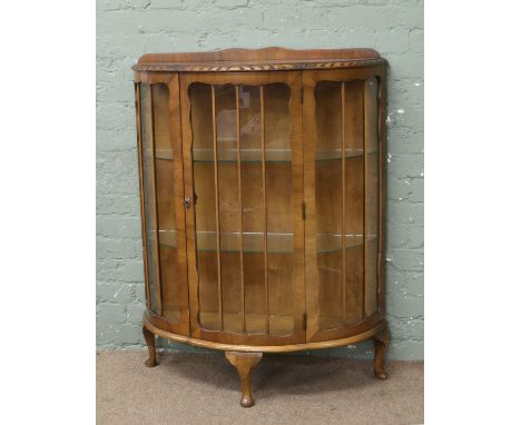 A 1940s walnut bow front china cabinet raised on cabriole feet.