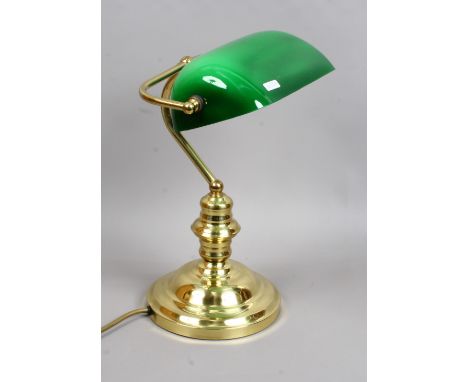 A brass based desk lamp with adjustable green glass shade.