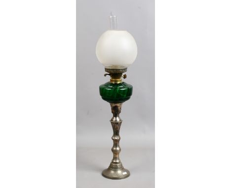 An oil lamp with silver plated base and green glass font.