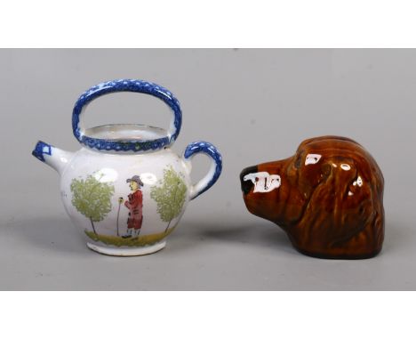 A treacle glazed pottery money box in the form of a dogs head and a Continental faience flask painted with figures.