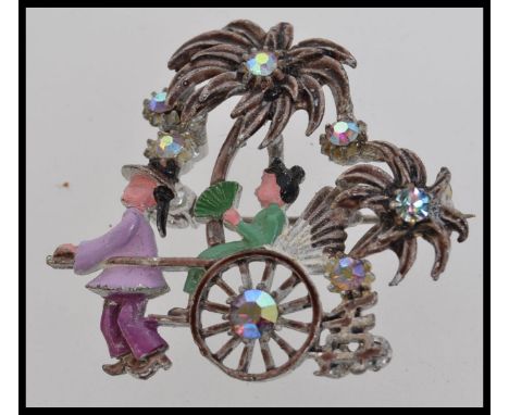 A 1950s white metal and enamel brooch with depicting a rickshaw with palm trees set with AB Rhinestones with a chinese symbol