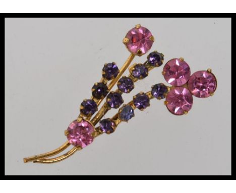 A vintage yellow metal pink and purple rhinestone flower spray brooch
