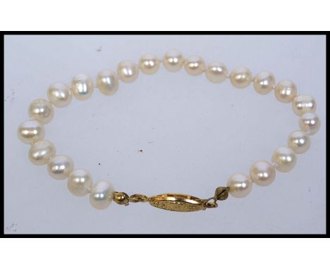 A vintage pearl bracelet strung with cultured pearls with yellow metal clasp. Measures 7 inches.