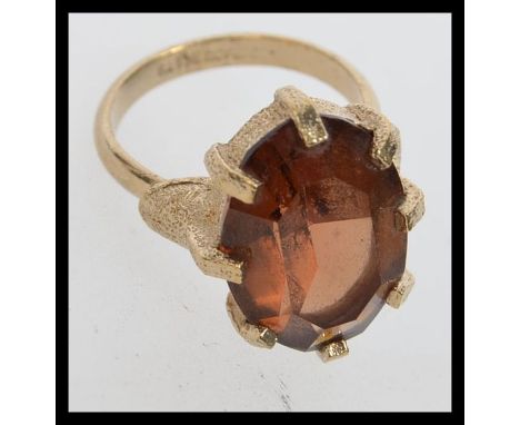 A vintage 1970s ring set with a large amber coloured gemstone. Marked Sarah Cov GB. For Sarah Coventry. Size N. Weight 7.5g.