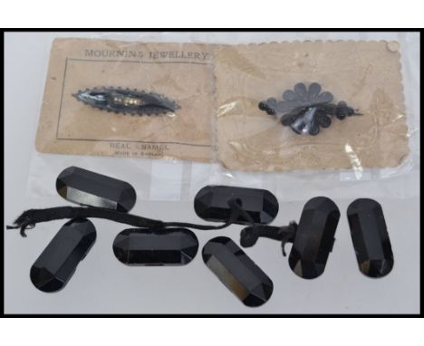 Two early 20th century funeral brooches on original cards one being bakelite the other enamel metal together with a quantity 