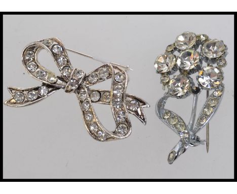 two vintage white metal brooches  one of a flower and the other a bow set with diamonte. Measures 4.5cms approx each.