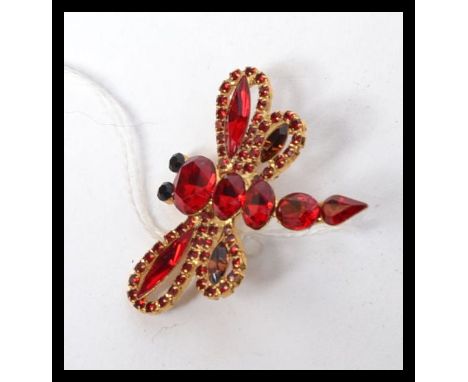 A Vintage yellow metal dragonfly brooch set with red paste stones with black bezel set eyes. Makers mark to verso. Measures 4