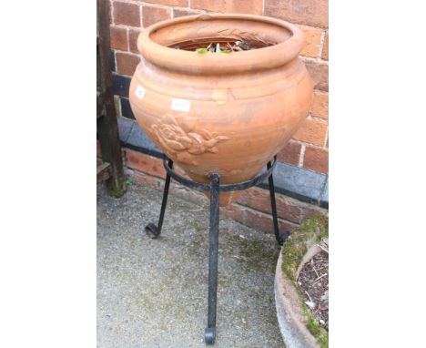 A cast terracotta garden planter supported on black finished metal three legged to stand 