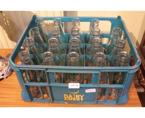 A selection of vintage Clyde Higgs milk bottles with various humorous script housed in an associated Dairy Crest crate 