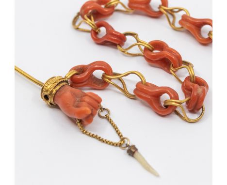 A 19th century coral and gold figa chained stick pin/hair decoration, comprising a 'figa' hand gripping a chain, gold pin and