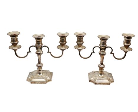 A pair of George I style silver three light candelabra, urn shaped sconces above shaped octagonal bases with knopped stems an