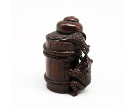 A 20th century hand carved hardwood netsuke, in the form of a Frog & Snail on barrel, signed to base on mother of pearl circu