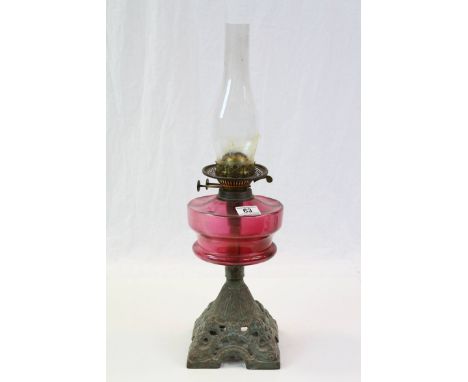 Oil lamp with ruby glass reservoir and cast metal base, height including glass shade approximately 59cm