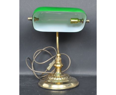 A 20th Century vintage bankers desk / table lamp light of brass construction having an adjustable green glass shade supported