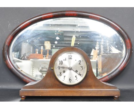 A 20th century wall hanging mirror and mantel clock. The mirror of an oval form with bevelled glass set in a mahogany colour 