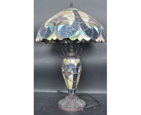 A contemporary Tiffany table lamp having a leaded shade with blue and green glass panels raised on a baluster form base with 