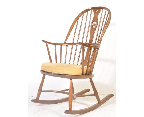 A mid century Ercol Swan pattern beech wood rocking chair. The armchair on sleigh rockers with turned legs united by stretche