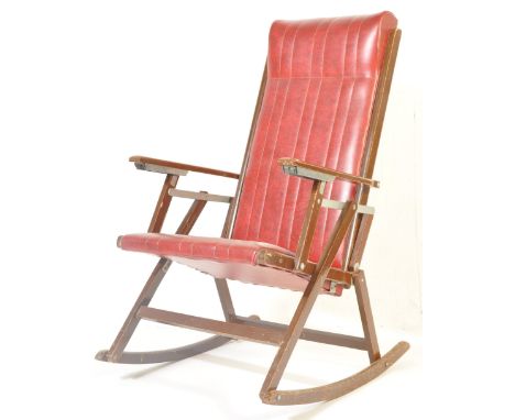 A retro vintage mid 20th century circa 1960s folding rocking chair having a stitched red vinyl seat with show wood elbow rest