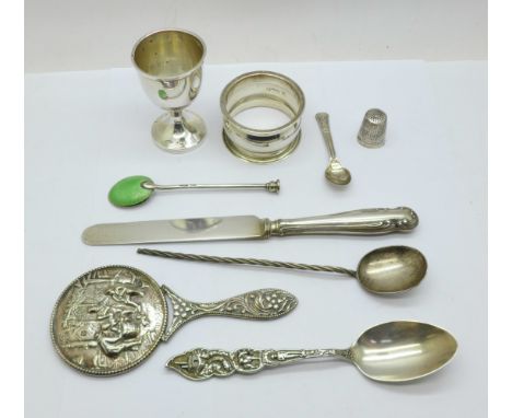 A collection of silver items; napkin ring, egg cup, knife, Charles Horner thimble, spoon with American pioneer decoration, a 