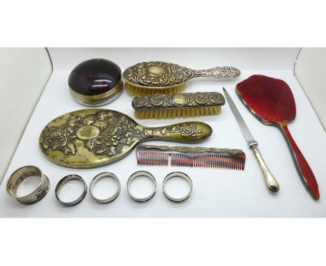 A collection of silver including five napkin rings, two silver backed brushes, a comb, a plated pot with faux tortoiseshell l