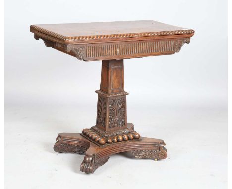 An early 19th century Anglo-Indian padauk fold-over card table, the hinged top with a gadrooned edge above a profusely carved