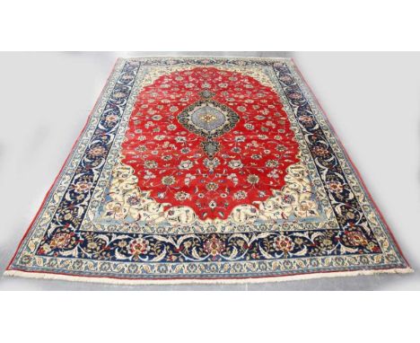 A Central Persian carpet, late 20th century, the red field with a shaped medallion, within a blue palmette and curled leaf bo