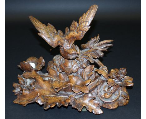 A Black Forest type carved desk and ink stand in the for of a bird of prey seated on foliage holding a songbird, 48 cm wide x