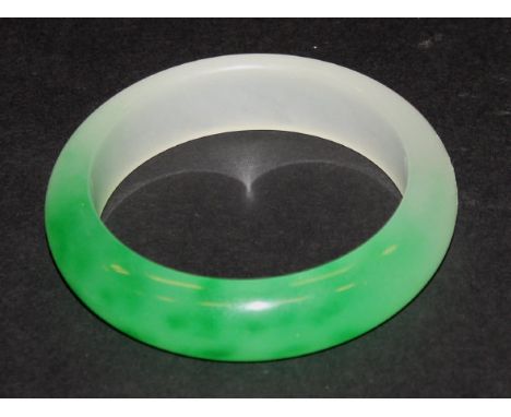 A two tone jade bangle of plain form and green and white colouring, 8 cm diameter
