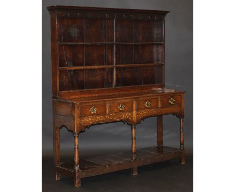 An early 19th Century oak dresser, the associated three tier boarded plate rack with iron cup hooks over four frieze drawers 