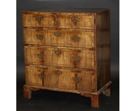 An early 18th Century walnut chest, the quartered feather banded and cross banded top with moulded edge above two short and t