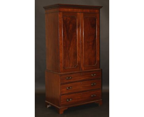 A 19th Century mahogany linen press of small proportions, the dentil cornice above two cupboard doors enclosing two shelves a