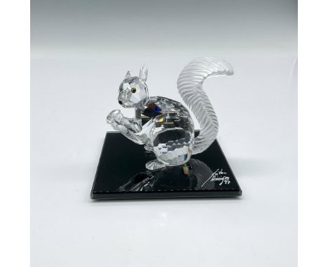 Clear crystal figural holding a nut, amber eyes, black nose and frosted, grooved tail. Swarovski backstamp. 208433. This item