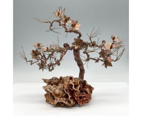 Hand crafted with twisted copper wire creating tree with branches and flowers. Sculpture is set on natural rust colored coral