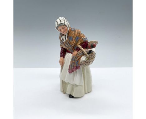 Hand painted figure of an elderly woman holding a basket with blankets and brushes. White, maroon and orange colorations. Roy