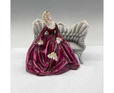 A semi-porcelain figure modeled as a blonde lady wearing a purple grown with gilded decorations sitting on couch with parasol