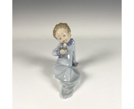 Adorable glossy figure of baby holding a pacifier in serene blue pastel tones. Lladro backstamp. Artist: Salvador DebonIssued