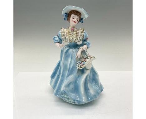 A figure modeled as a lady wearing a light blue grown with gilded decorations, holding a basket of flowers in her hand. Flore